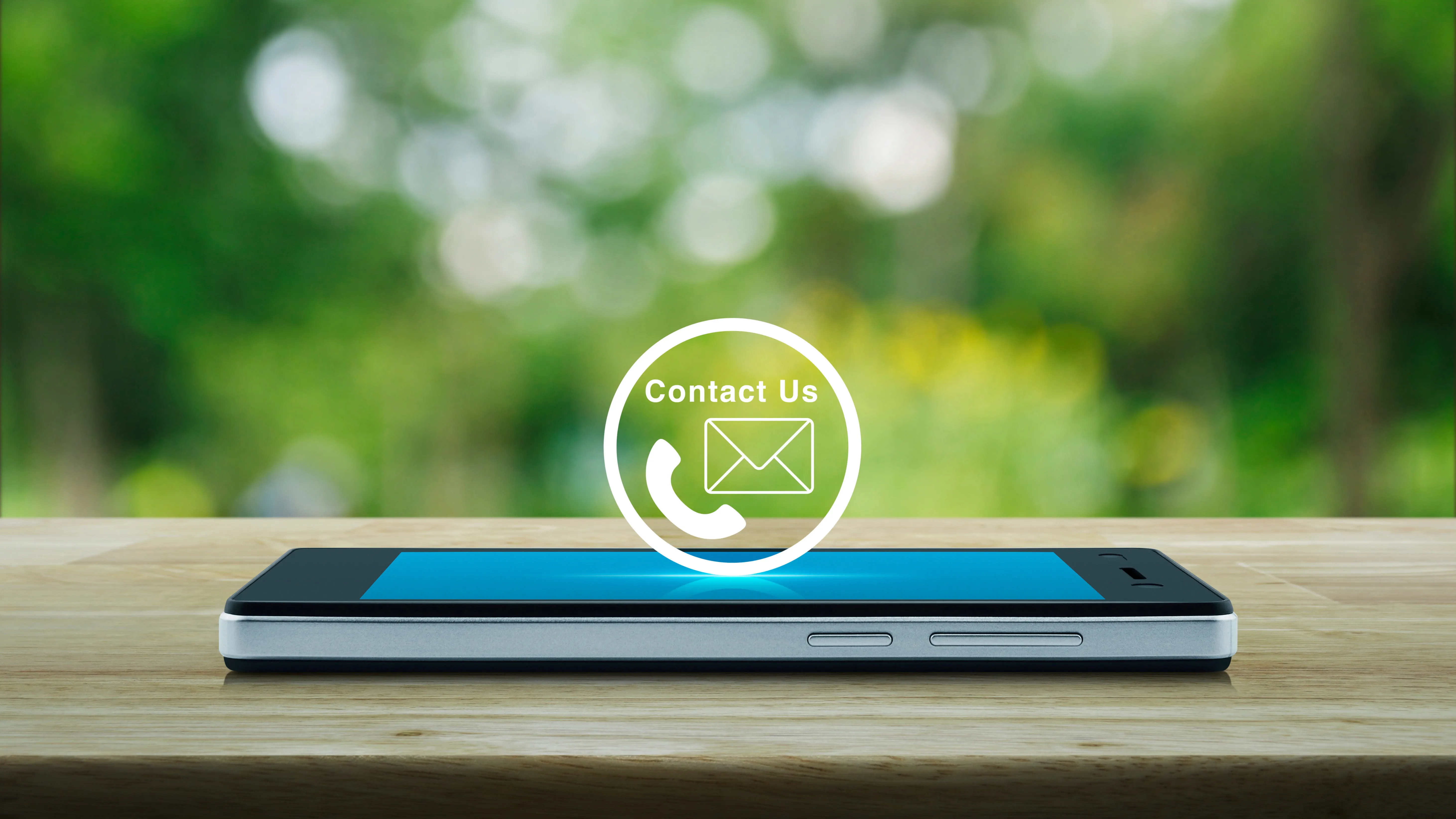 Smartphone on a wooden surface with contact icons for phone and email