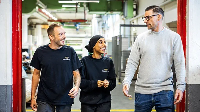Group of workers walking and laughing in a factory 