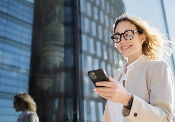 Person using a smartphone in front of a modern glass building